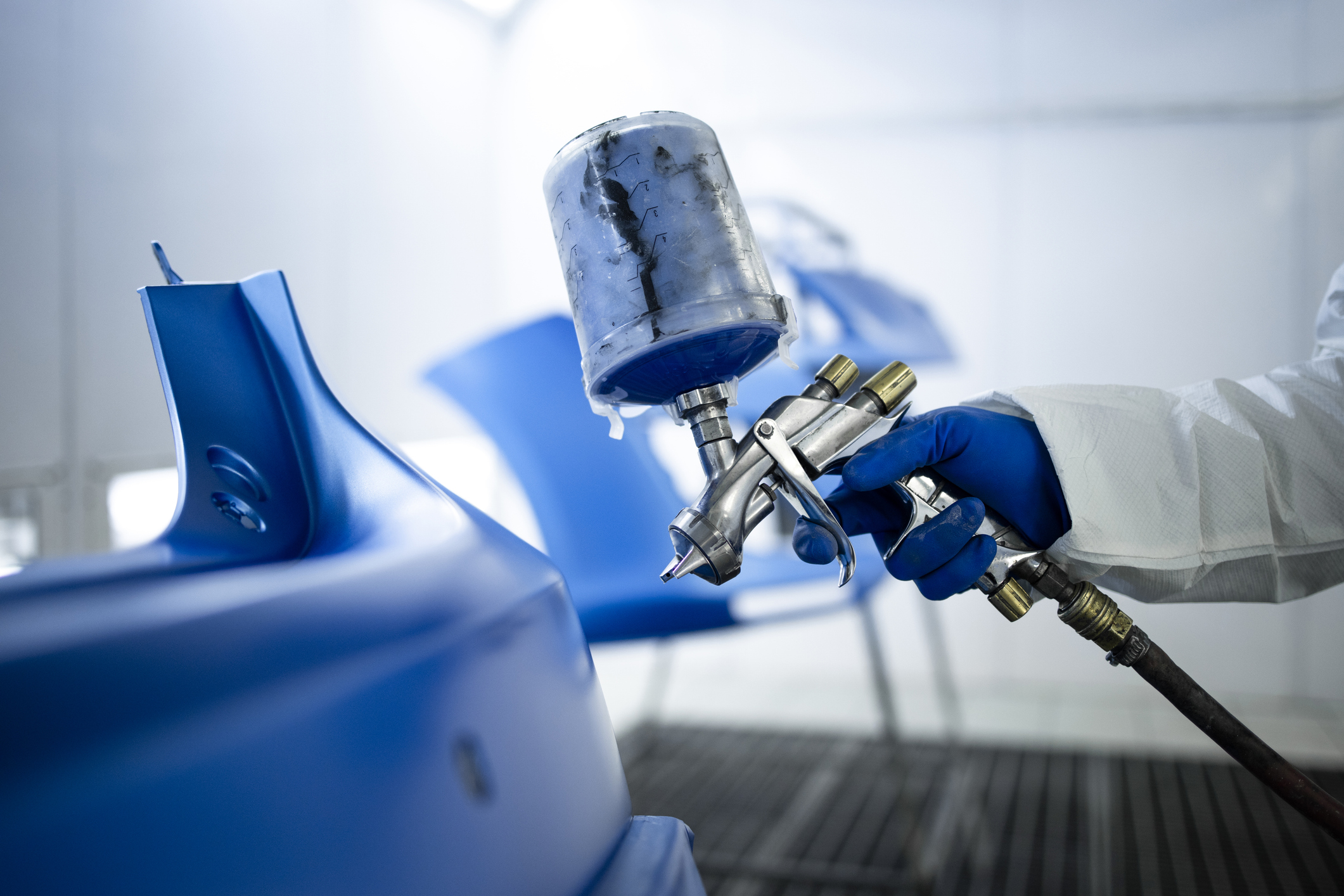 Technician applying factory-matched paint to a repaired body panel